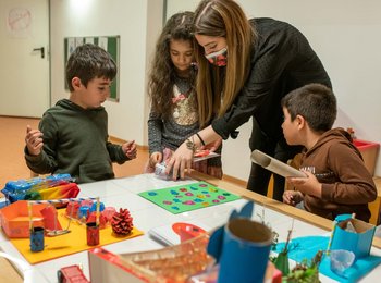 Kinder tüfteln mit der Unterstützung einer Mitarbeiterin im Kindermuseum Mondo mio